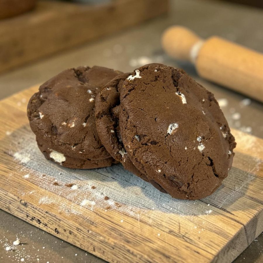 Chocolate s'mores cookies with marshmallow bits on a wooden board from the bakery's Instagram